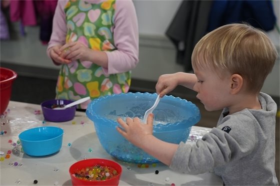 young boy playing with Orbeez in a blue bowl
