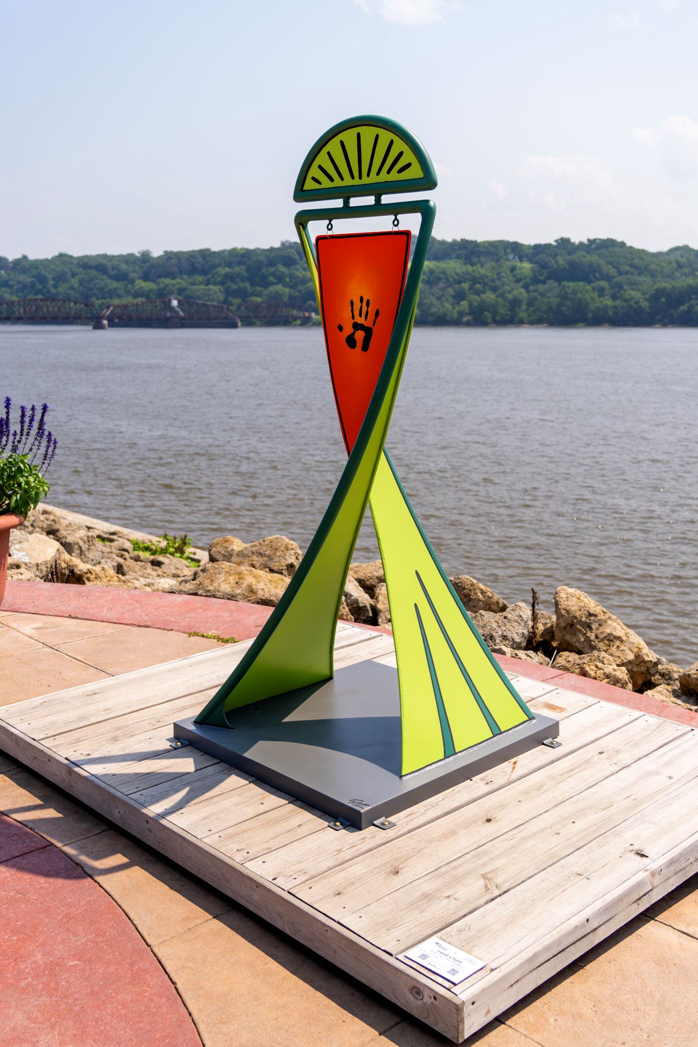 six feet tall vibrant green sculpture with an orange plaque with a symbol of a hand